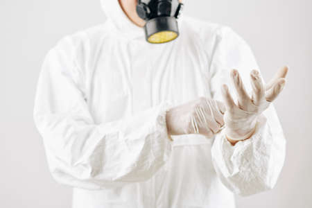 Worker putting on hazmat suit, protective gloves and mask before disinfecting streets in city under quarantineの写真素材