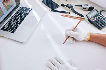 Architect working at his table and drawing blueprint on white blank sheetの写真素材
