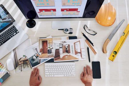 Professional interior designer looking at printed photos of rooms on his desk, view from aboveの写真素材