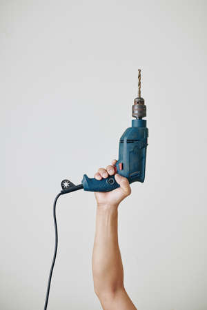 Professional builder raising hand with electric drill, isolated on light greyの写真素材