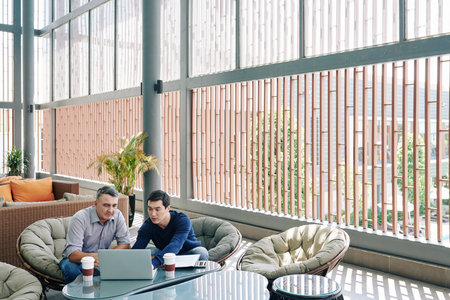 Business colleagues meeting in office lounge area to discuss details of project