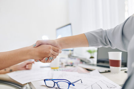 Creative team managers shaking hands after finishing work on big projectの写真素材