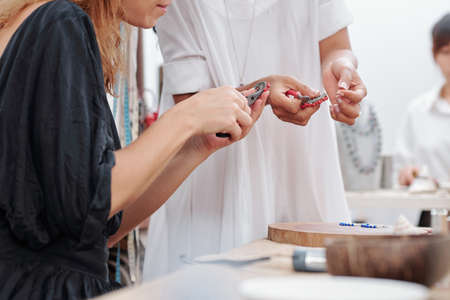 Women with pliers making natural stones earrings at workshopの写真素材