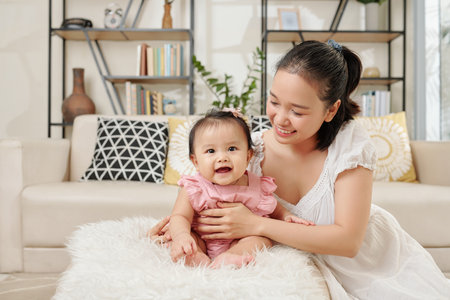 Happy mother putting her little smiling daughter on furry fluffy small stool