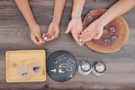 Hands of women checking beautiful earrings they made in workshop with natural stone beadsの写真素材