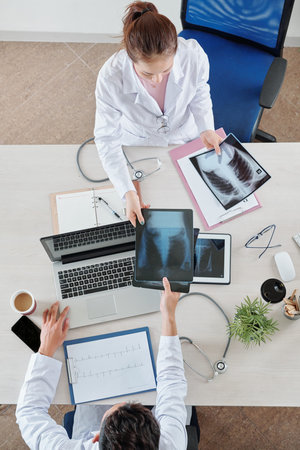 Nurse giving lungs x-ray of patient to pulmonologist, view from above