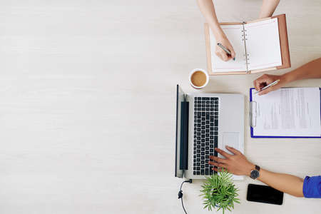 Businessman checking contract and answering e-mails when his assistant taking notes in plannerの写真素材