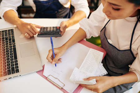 Cafe owners checking bills and receipts, taking notes and making calculationsの写真素材