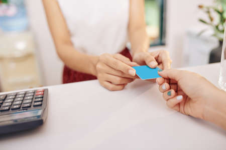 Close-up image of female customer giving credit card to waitress or receptionist to pay for food or serviceの写真素材