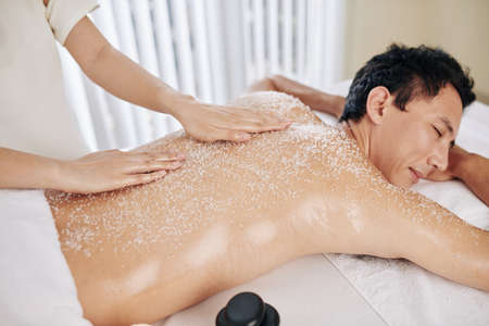 Mature mixed-race man enjoying exfoliating massge at spa resortの写真素材