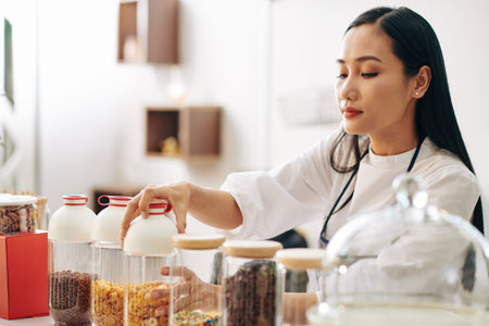 Pretty young waitress opening container with cornflakes when making breakfast for customer