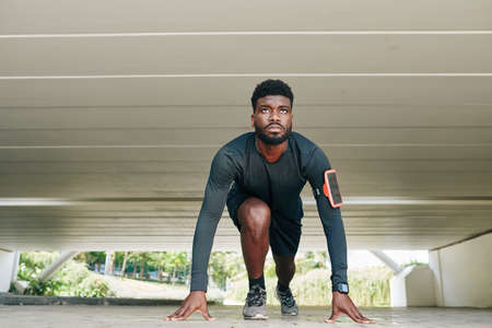 Concentrated young fit sprinter on start line of the track ready to runの写真素材