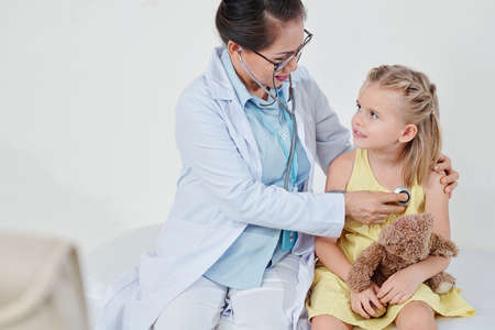 Pediatrician with stethoscope checking lung sounds of little patientの写真素材