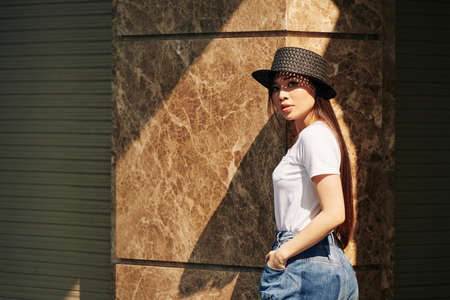 Beautiful young Asian woman in small hat turning back and looking at cameraの写真素材