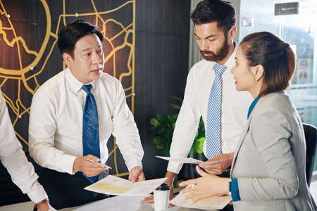 Experienced Vietnamese entrepreneur talking to his team and reprioritizing initiatives to take advantage of new opportunitiesの写真素材