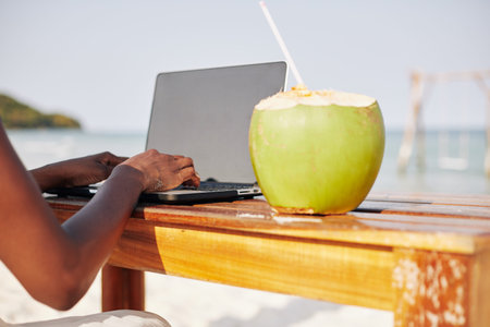 Close-up image of young woman enjoying her vacation on tropical beach, drinking coconut water and...
