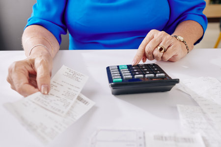 Close-up image of aged woman checking her bills and making calculations