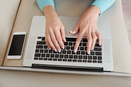 Hands of young woman answering e-mails from collegues and clients, view from aboveの写真素材