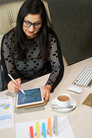 Mature woman working as graphic designer using digital tablet computer and stylus pen, vertical high...