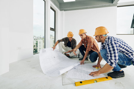 Middle Eastern construction engineers sitting on hunkers in empty room of unfinished building...