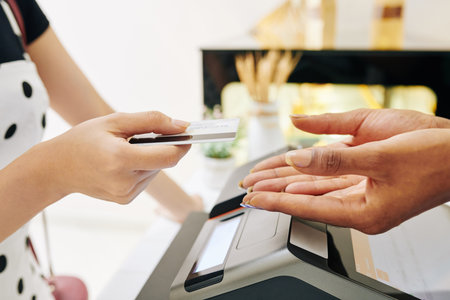 Close-up image of female customer giving credit card to bakery shop owner to pay for the order