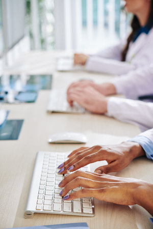 Close-up image of female scientist working on computer and entering important scientific data and...