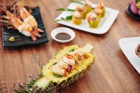 Table with with South Asian dishes like spiny lobsters, stuffed zuccini and fried rice served in pineapple bowlの写真素材