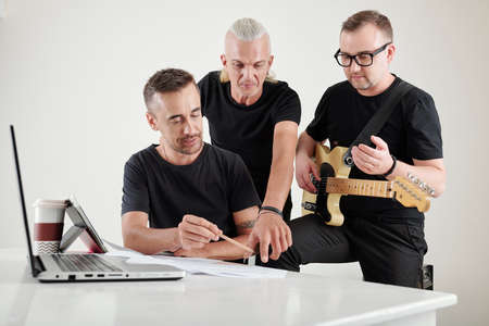 Composer showing new melody he created to singer and guitar player of music bandの写真素材