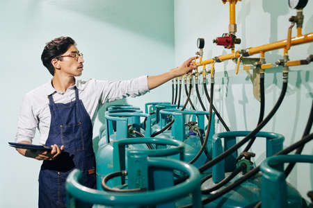 Coffee roastery worker with tablet computer checking pressure in gas pipesの写真素材
