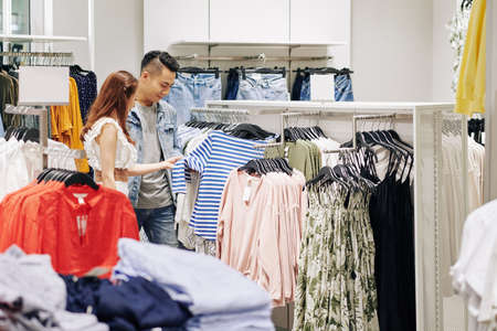 Young couple buying striped shirt in shopping mallの写真素材