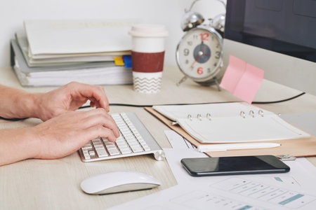 CLose-up image of businessman working on computer at his desk with opened planner, smartphone and...