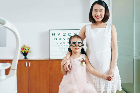 Happy smiling mother and her little daughter in test glasses in office of optometrist
