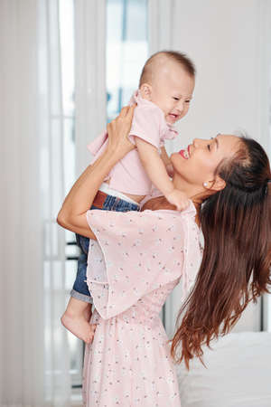 Happy young mother in floral dress lifting her smiling cute little sonの写真素材