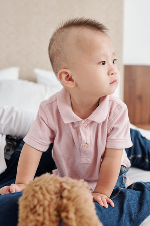 Portrait of cute curious Asian baby boy crawling on bed and looking around