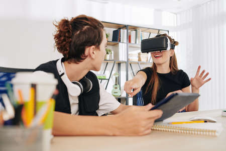 Cheerful teenage boy with tablet watching his sister testing new VR application he createdの写真素材