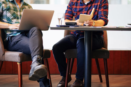 Cropped image of young people working on project at cafe table, answering e-mails and filling...