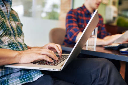 Close-up image of universiry students working on laptop when sitting at local cafeの写真素材