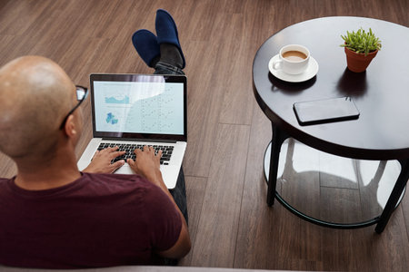 Entrepreneur sitting on the floor next to coffee table and working on monthly financial report