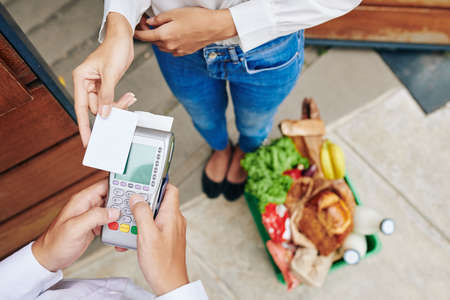 CLose-up image of female customer paying with credit card for groceries orderの写真素材