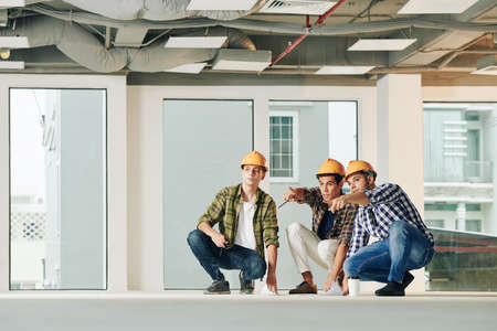 Group of young engineers discussing plan of service lines before starting work inside new buildingの写真素材