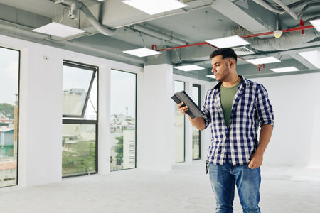 Serious young contractor checking building inspection report on digital tablet