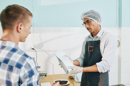 Roastery worker showing packed roasted coffee to sales manager