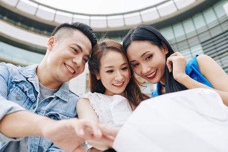Excited happy Vietnamese young people looking inside of shopping bag