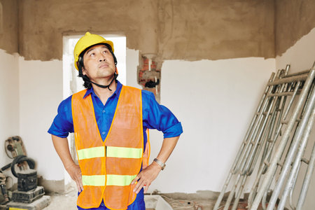 Pensive unhappy builder looking at water stains on ceiling and planning repairing of leaking roof