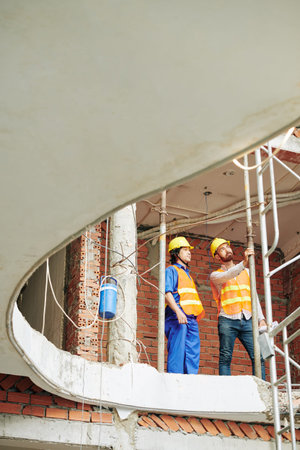 Multi-ethnic foremen checking metal gas pipes in wall of building under construction