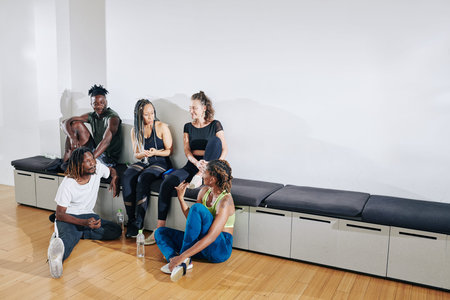 Multi-ethnic group of young dancers discussing performace and gossiping after training in studio