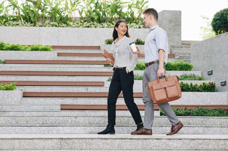 Young positive entrepreneurs walking outdoors and discussing news and ideasの写真素材