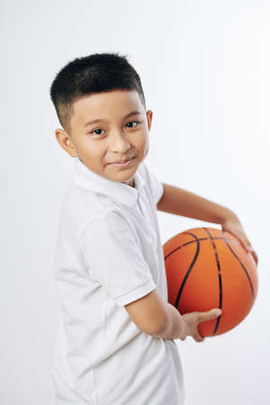 Portrait of cute smiling preteen Asian boy posing with basketball ballの写真素材