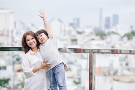 Portrait of joyful Vietnamese woman and her adorable little daughter standing on observation platformの写真素材