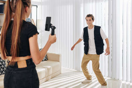 Teenage girl asking friend to make dance move when they are filming creative video for blog or social mediaの写真素材